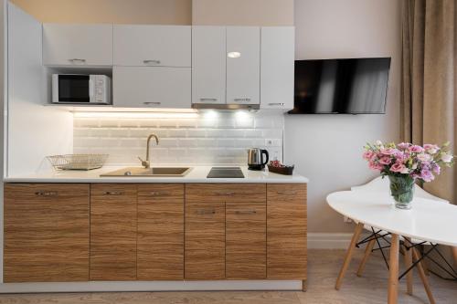 a kitchen with white cabinets and a sink and a table at Apartamenty w Klaudynie in Klaudyn