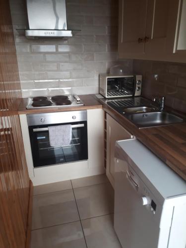 a kitchen with a stove top oven next to a sink at Apartment in the Heart of Kerry in Knockeen Cross Roads