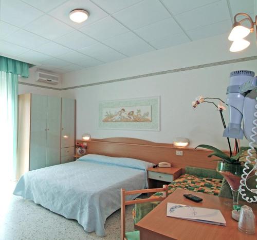 a bedroom with a bed and a desk and a table with a desk at Hotel Katia in Cesenatico