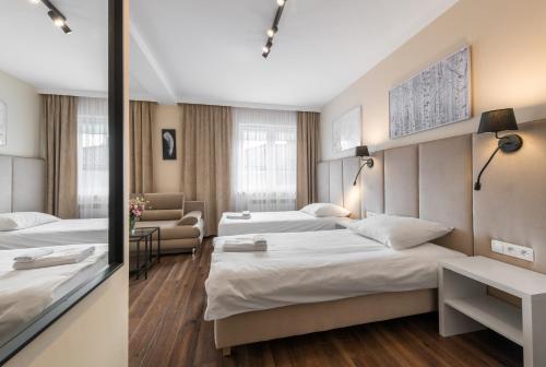a hotel room with three beds and a couch at Apartamenty w Klaudynie in Klaudyn