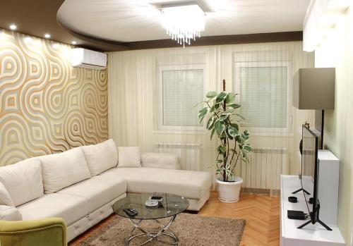 a living room with a white couch and a table at Bane Apartmani in Kraljevo