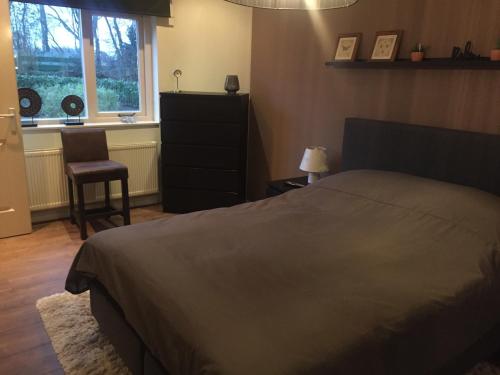 - une chambre avec un lit, une chaise et une fenêtre dans l'établissement Rumah kita, bungalow met 2 slaapkamers in het mooie Drenthe, à Erm