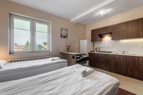 a room with two beds and a sink and a kitchen at Apartamenty w Klaudynie in Klaudyn