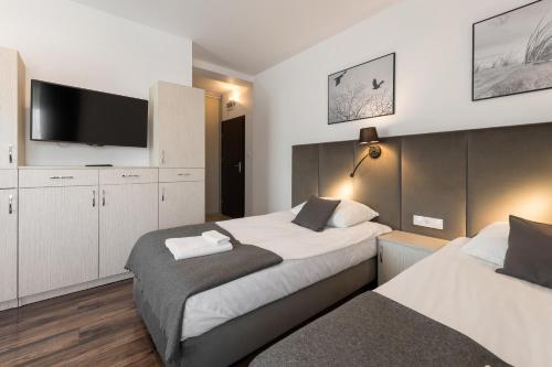 a bedroom with two beds and a flat screen tv at Apartamenty w Klaudynie in Klaudyn