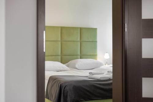 a bedroom with a large bed with a green headboard at Apartamenty w Klaudynie in Klaudyn