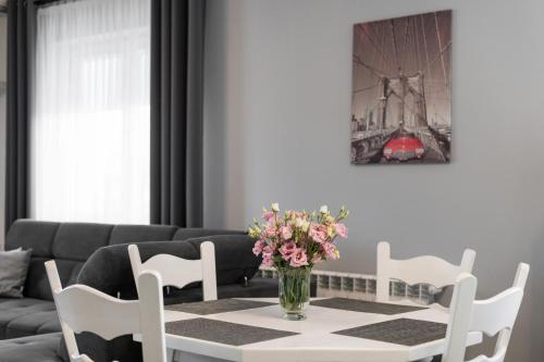 a living room with a table with a vase of flowers at Apartamenty w Klaudynie in Klaudyn