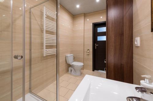 a bathroom with a toilet and a glass shower at Apartamenty w Klaudynie in Klaudyn