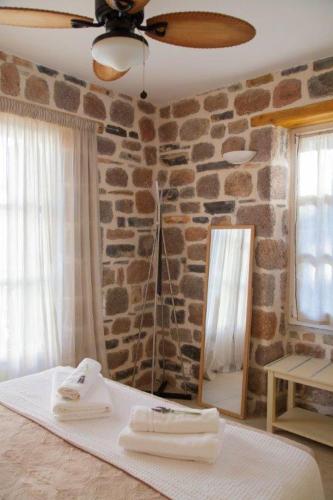 a bedroom with a stone wall with a bed and a mirror at Lithos Residence Poros in Poros