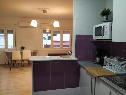 a kitchen with purple walls and a kitchen island with a microwave at Apartamento Cayetano in Ronda