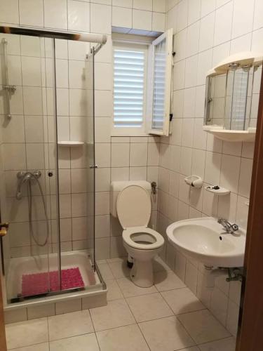 a bathroom with a shower and a toilet and a sink at Apartmani Škarić in Lopar