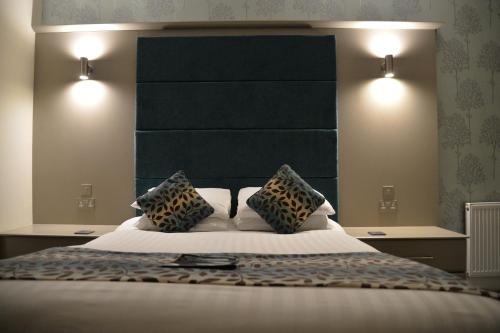 a bedroom with a large bed with a large headboard at Lauriston & Lawton Court Hotel in Llandudno
