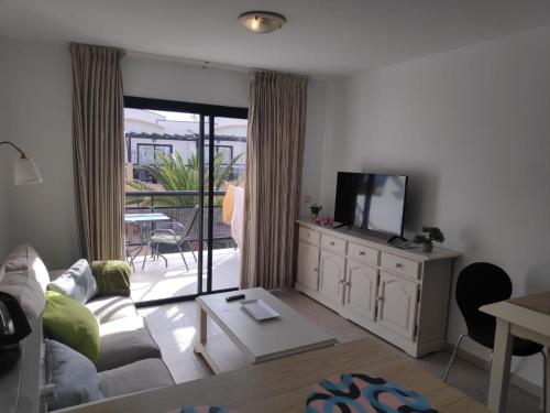 ein Wohnzimmer mit Sofa und Fernseher in der Unterkunft Apartamento SUNNY Complex Amaya Fuerteventura in Costa de Antigua