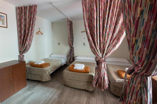 バルセロナにあるホステル LIWIのベッド2台、ソファ、カーテンが備わる客室です。