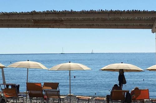 a group of chairs and umbrellas on a beach at Home La Quiete. Two Bedrooms, 250m from the Beach in Ospedaletti