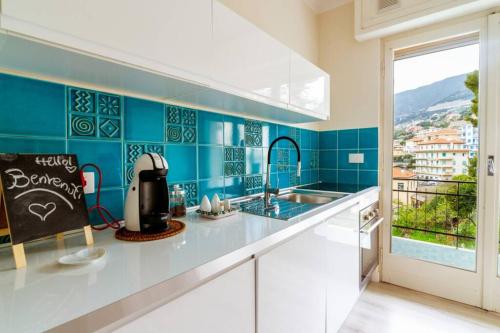 a kitchen with blue tiled walls and a counter top at Home La Quiete. Two Bedrooms, 250m from the Beach in Ospedaletti