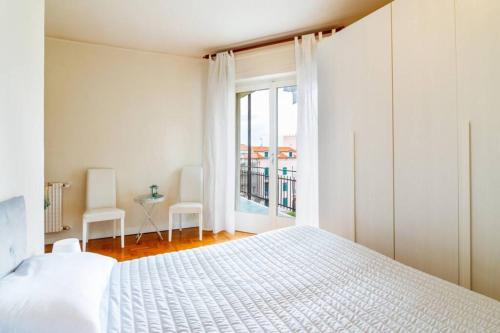a white bedroom with a bed and a window at Home La Quiete. Two Bedrooms, 250m from the Beach in Ospedaletti