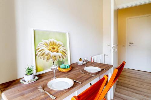 a wooden table with two plates and a flower painting on the wall at Home La Quiete. Two Bedrooms, 250m from the Beach in Ospedaletti
