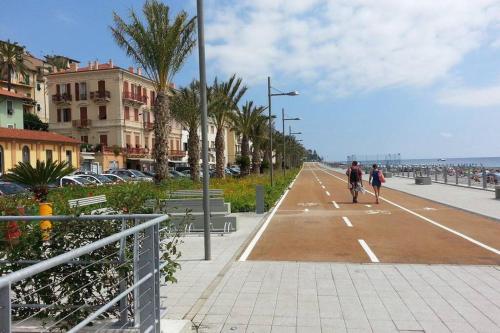two people riding a bike down a street next to the ocean at Home La Quiete. Two Bedrooms, 250m from the Beach in Ospedaletti