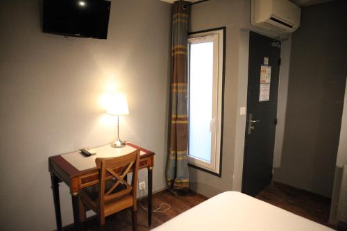 a room with a desk with a lamp and a window at Arnaud Bernard Hôtel in Toulouse
