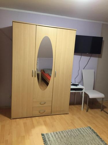 a wooden cabinet with a mirror in a room at Fekete Macska Panzió in Tata