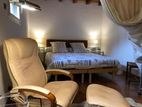 une chambre avec un lit, une chaise et une table dans l'établissement La ferme de Pouzatel proche Bonaguil, à Fumel