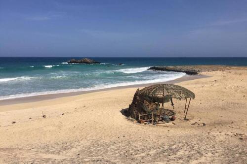 a beach with an umbrella on the sand at 4 Sterne Appartment Sal Kap Verden in Prainha