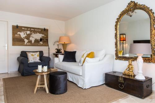a living room with a white couch and a mirror at Souterrain Zuid-Duinen -Free Parking in Zandvoort