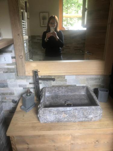 une femme prenant une photo d'un lavabo dans une salle de bains dans l'établissement Monolocale di charme a due passi da courmayeur, à Pré-Saint-Didier