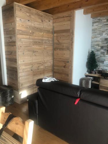 a living room with a black couch and a wooden wall at Monolocale di charme a due passi da courmayeur in Pré-Saint-Didier