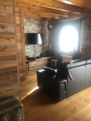 a living room with a leather couch and a window at Monolocale di charme a due passi da courmayeur in Pré-Saint-Didier