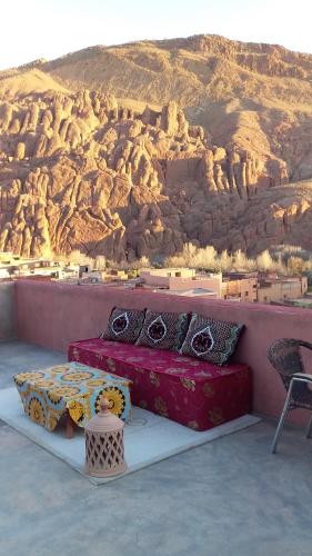 a bed with pillows in front of a mountain at Maison D'hote Amazir in Boumalne
