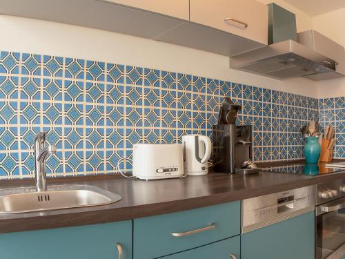 a kitchen with a sink and a blue tiled wall at Seesterne Residenz in Konstanz