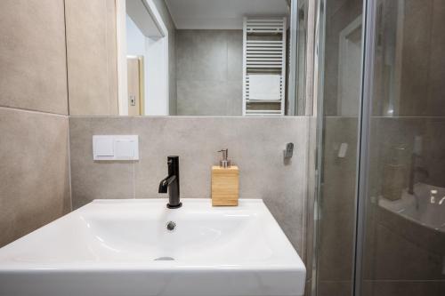a bathroom with a white sink and a shower at Marina Apartments ZOO in Wrocław