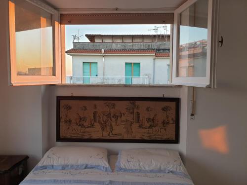 ミントゥルノにあるvacanze al mareのベッドルーム1室(窓、ベッド上の絵画付)