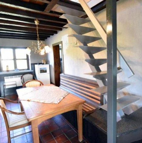 a dining room with a table and a spiral staircase at Huis Den Keibilk in Heuvelland