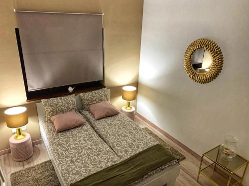 1 dormitorio con 1 cama con 2 lámparas y espejo en Panoráma apartman, en Alsóörs