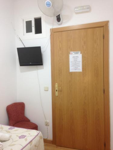 Habitación con puerta de madera y silla roja. en Hostal Nersan2, en Madrid