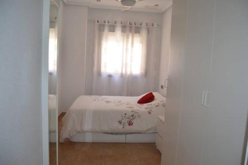 een witte slaapkamer met een bed en een raam bij Apartamento centrico in Santa Pola