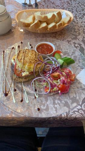 a table with a sandwich and a salad and a basket of bread at Zhaylau Hotel in Shchūchīnsk