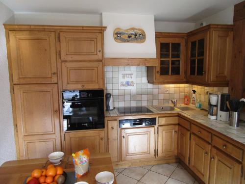 a kitchen with wooden cabinets and a table with oranges at La Ferme de Sous-Lachat in Samoëns
