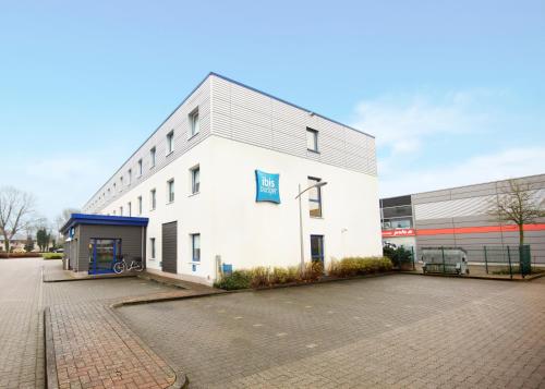 a white building with a blue sign on the side of it at ibis budget Flensburg Handewitt in Handewitt