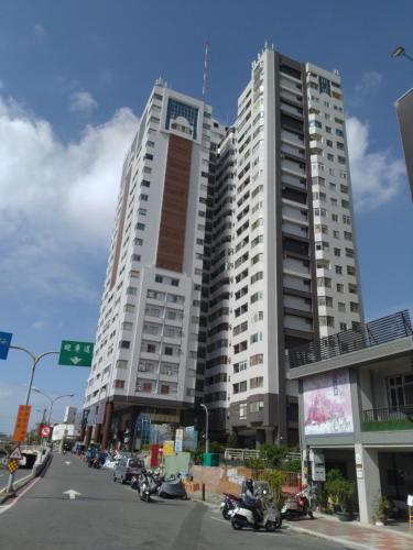 台南的住宿－Happy宅，一座高大的白色建筑,前面有汽车停放