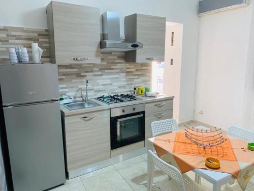a kitchen with a white refrigerator and a table with chairs at Casa Vacanze San Nicolò in Militello in Val di Catania