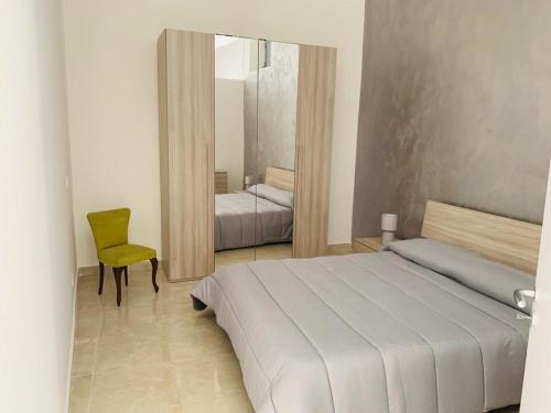 a bedroom with a bed and a chair and a mirror at Casa Vacanze San Nicolò in Militello in Val di Catania