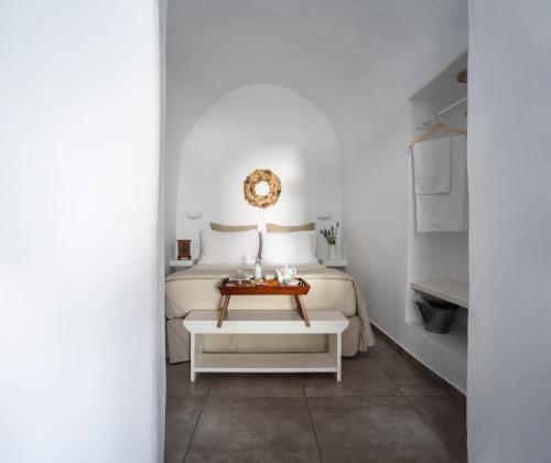 a white bedroom with a bed and a table at Arvanitis Cave Village in Akrotiri