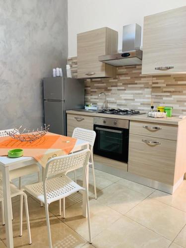 een keuken met een tafel en stoelen en een fornuis bij Casa Vacanze San Nicolò in Militello in Val di Catania