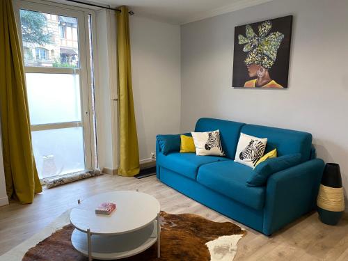 a living room with a blue couch and a table at Maison de ville de 55m2 refait à neuf in Verneuil d’Avre et d’Iton