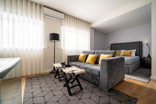 een woonkamer met een grijze bank en gele kussens bij Bracara Guest House "Campo das Hortas" in Braga