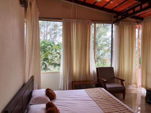 a bedroom with a bed and a chair and a window at LAZY DAYS Wayanad in Cherambādi