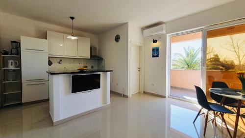 a kitchen with a white counter and a table and chairs at Apartman Petar in Ražanac